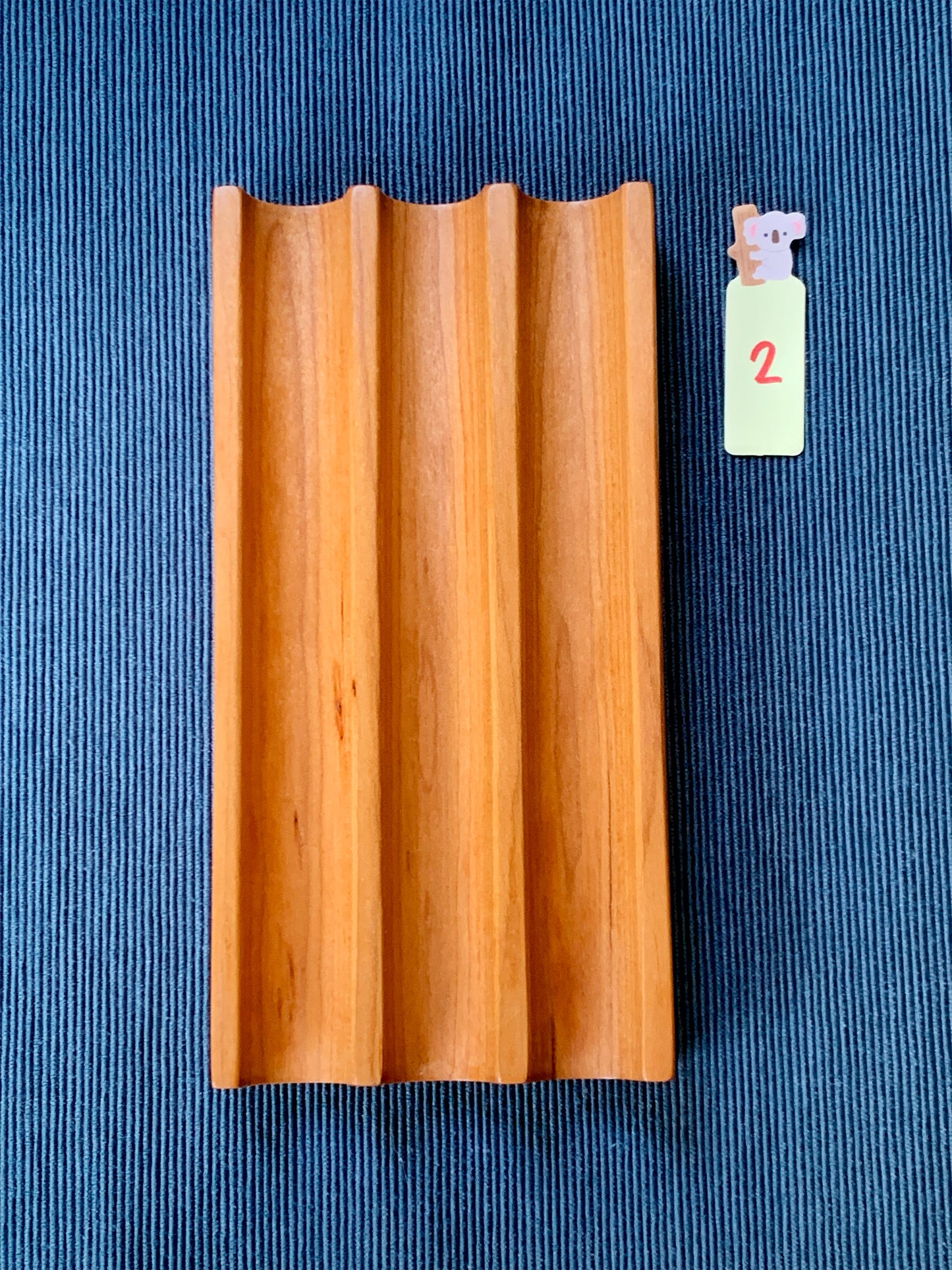 Elegant Kaze cherry pen tray with three smooth slots – shown on a deep blue textured backdrop. Tray #2