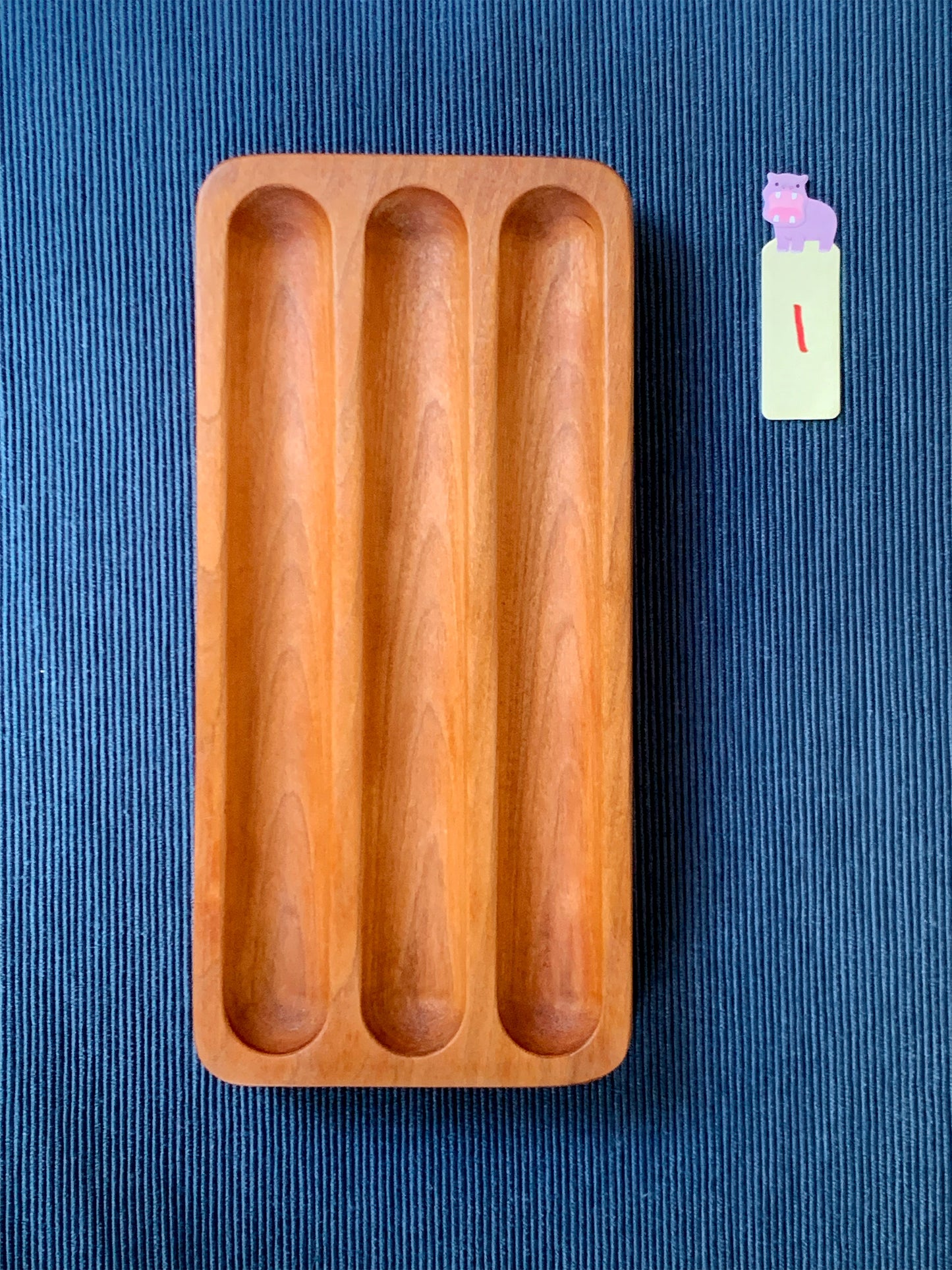 Elegant Shizuku cherry pen tray with three smooth slots – shown on a deep blue textured backdrop. Tray #1