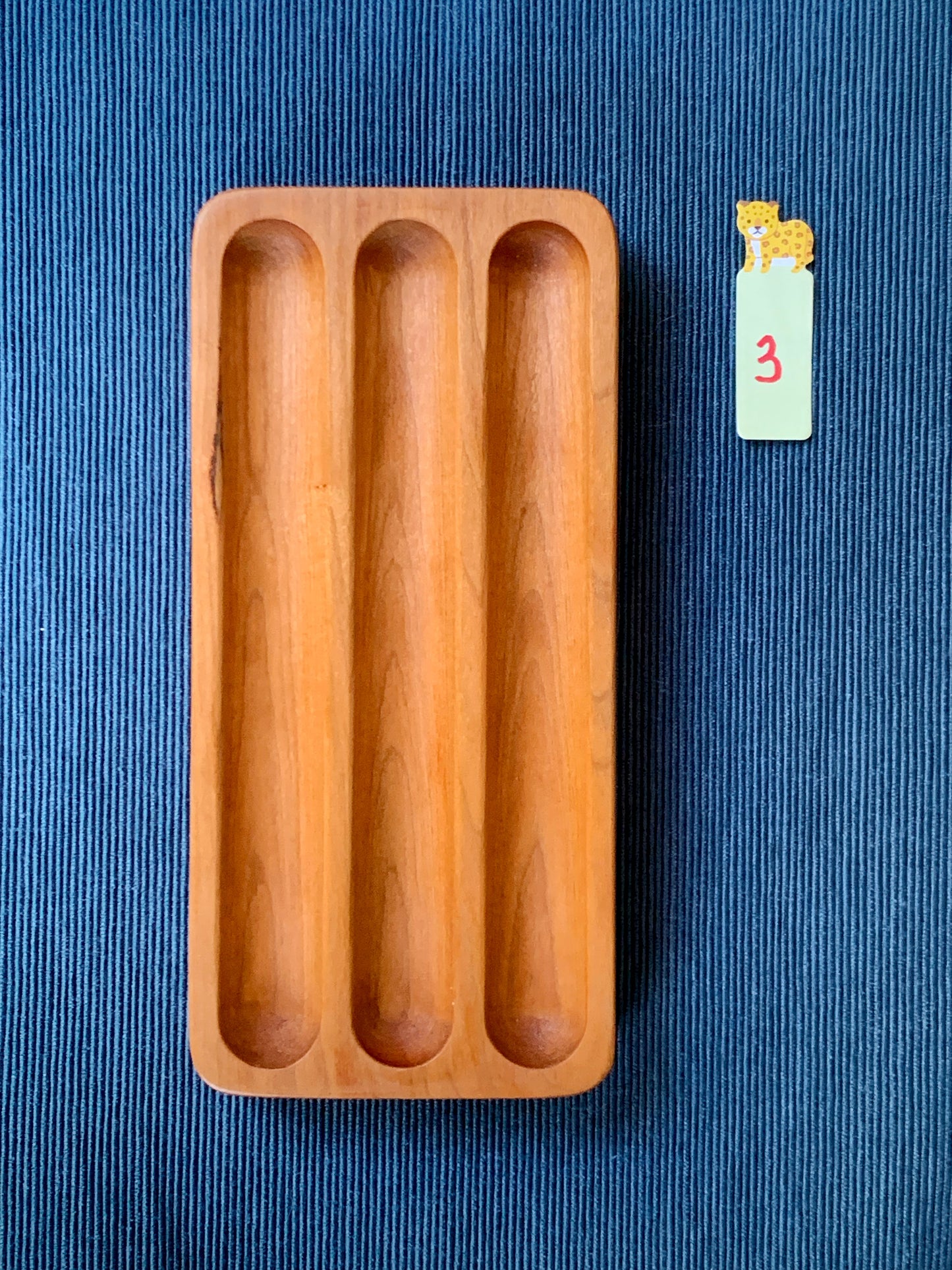 Elegant Shizuku cherry pen tray with three smooth slots – shown on a deep blue textured backdrop. Tray #3