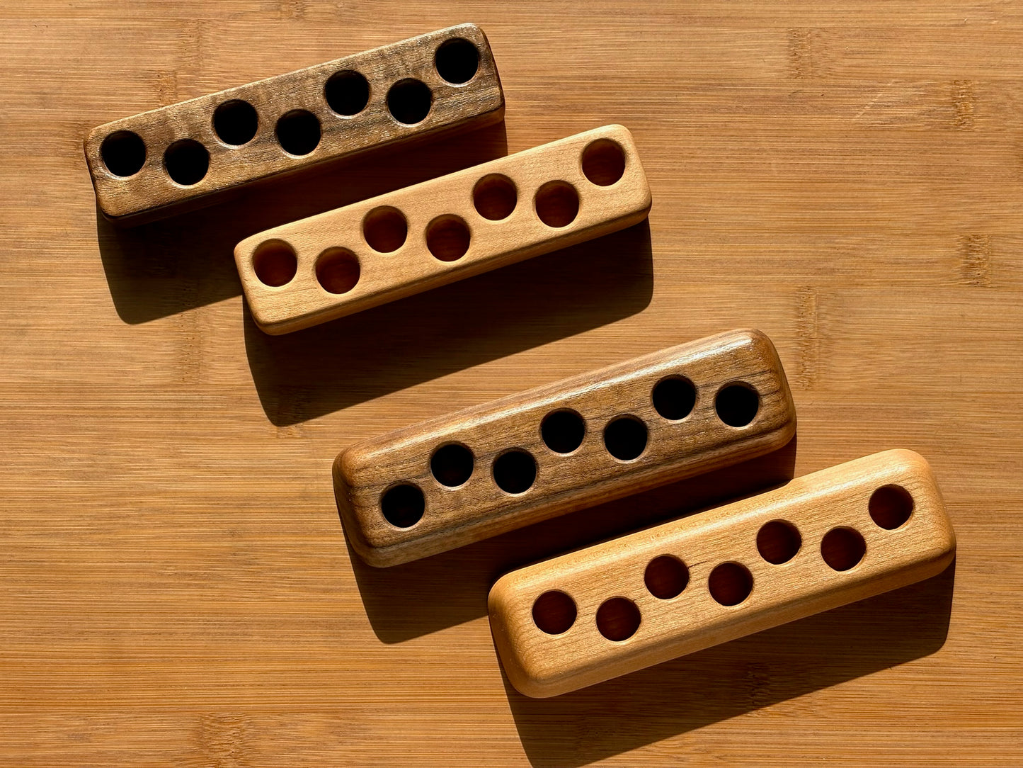 Collection of wooden ink sample vial holders in various woods and base styles, each holding seven vials