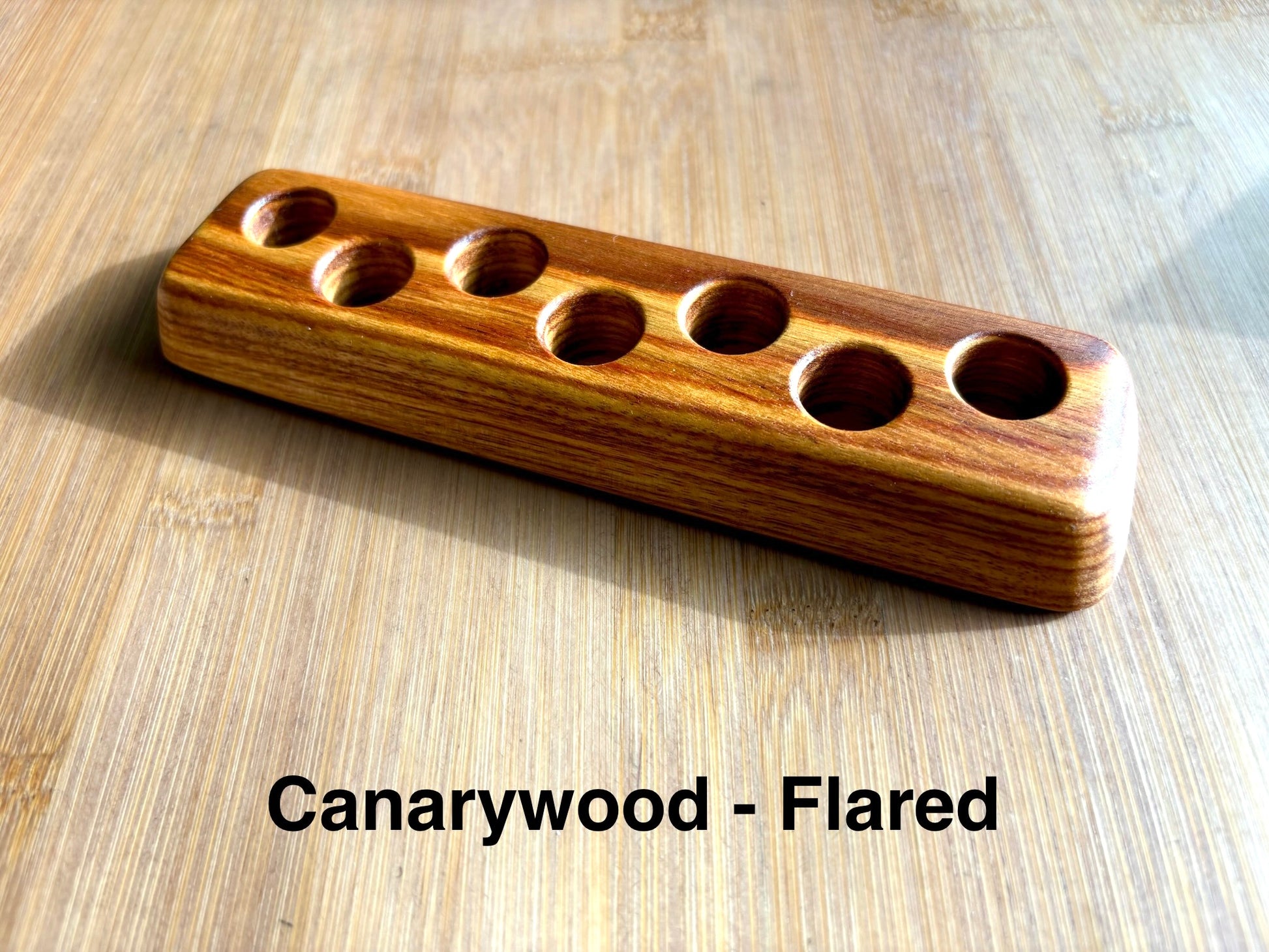 Flared-base canarywood ink sample vial holder with seven evenly spaced vial holes