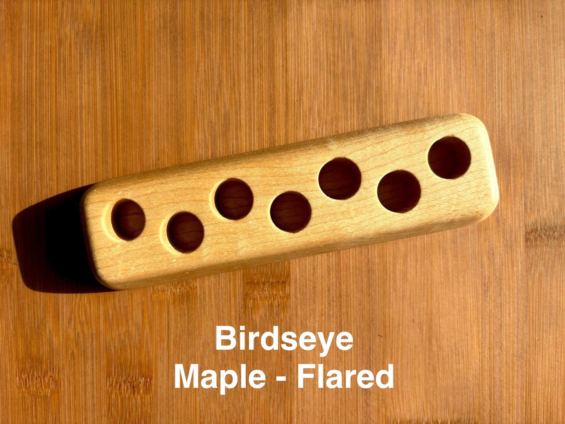 Birdseye maple ink sample vial holder with flared base, holding seven ink vials in staggered arrangement