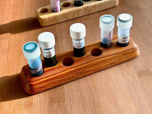Handcrafted wooden ink sample vial holder in canarywood wood with flared base, holding seven ink vials on a light wood desk.